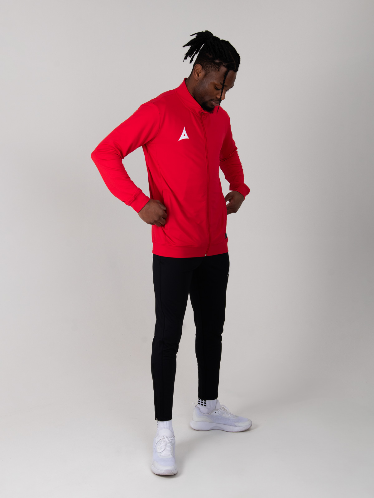 a model looking at the pockets of the avec red full zip tracksuit jacket made of polyester