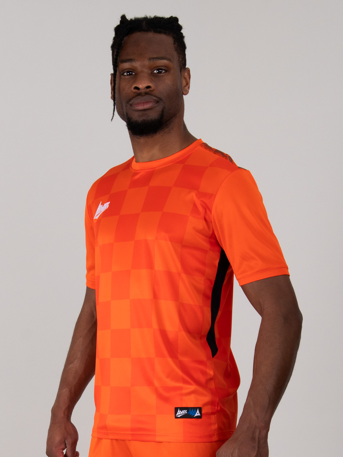 a man is wearing a bight orange football shirt which features a chequerboard design