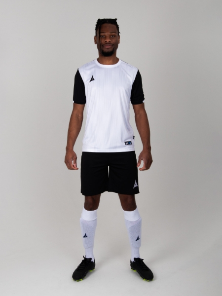 A football player is wearing a black and white football shirt, black shorts and white socks