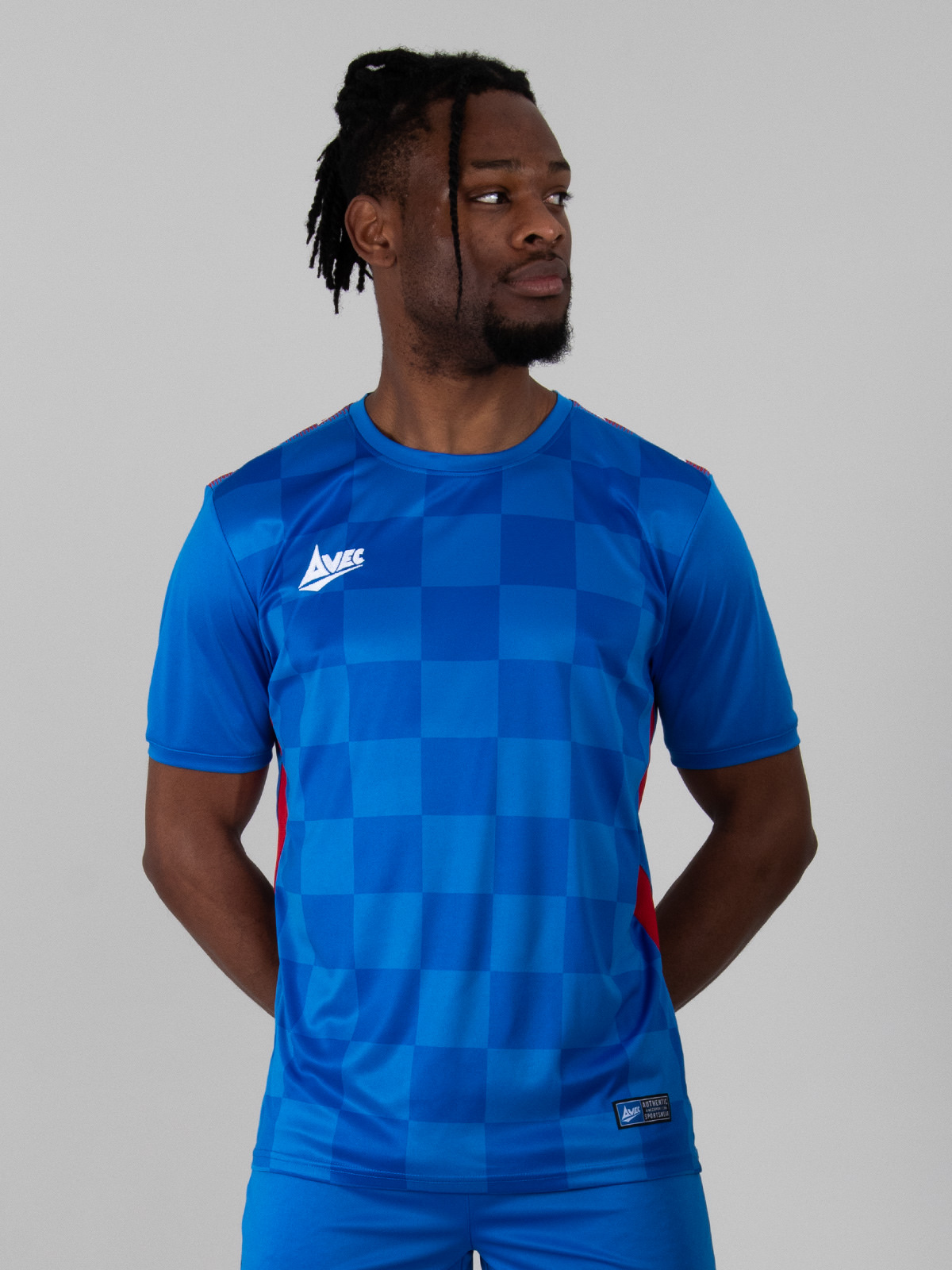 adult model is wearing a two-tone royal blue chequered football shirt with red side panels.