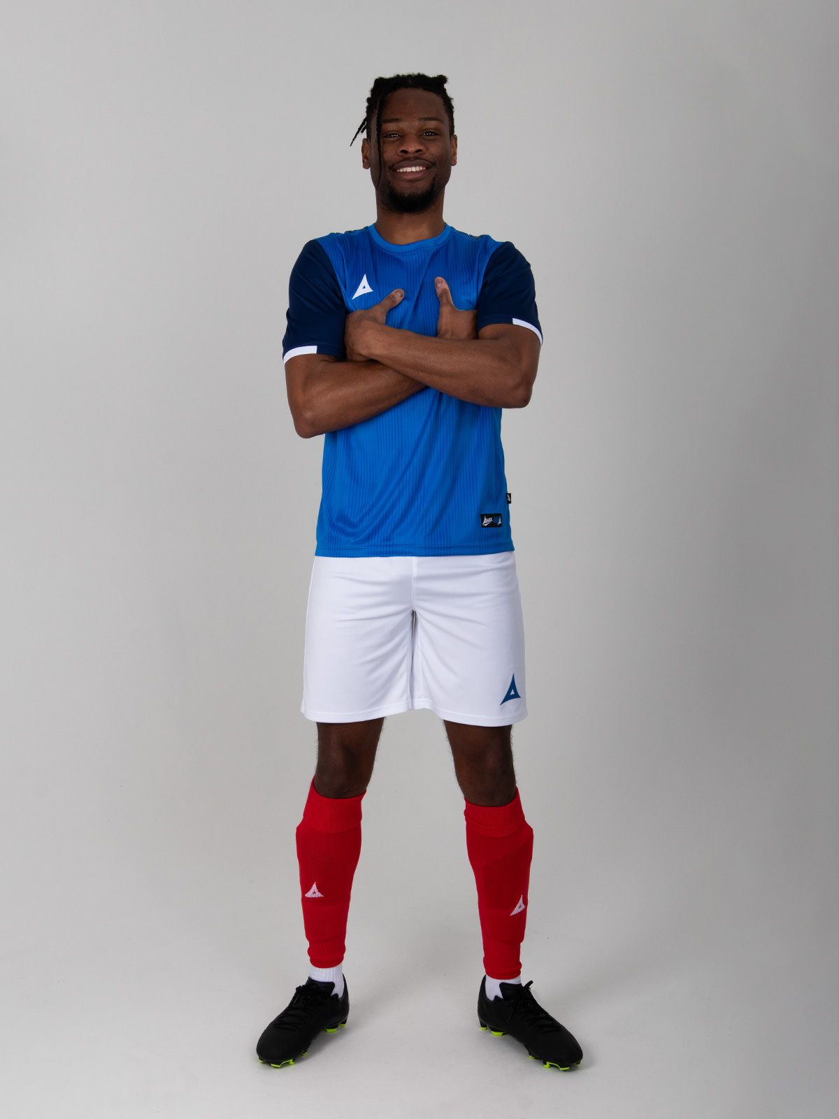a man is wearing a royal blue and navy football shirt, combined with white shorts and red socks, akin to the france kit.