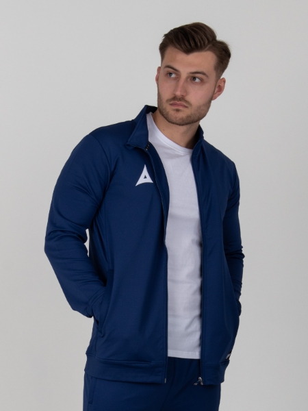 A man is wearing an unzipped navy tracksuit jacket, over the top of a white t-shirt.