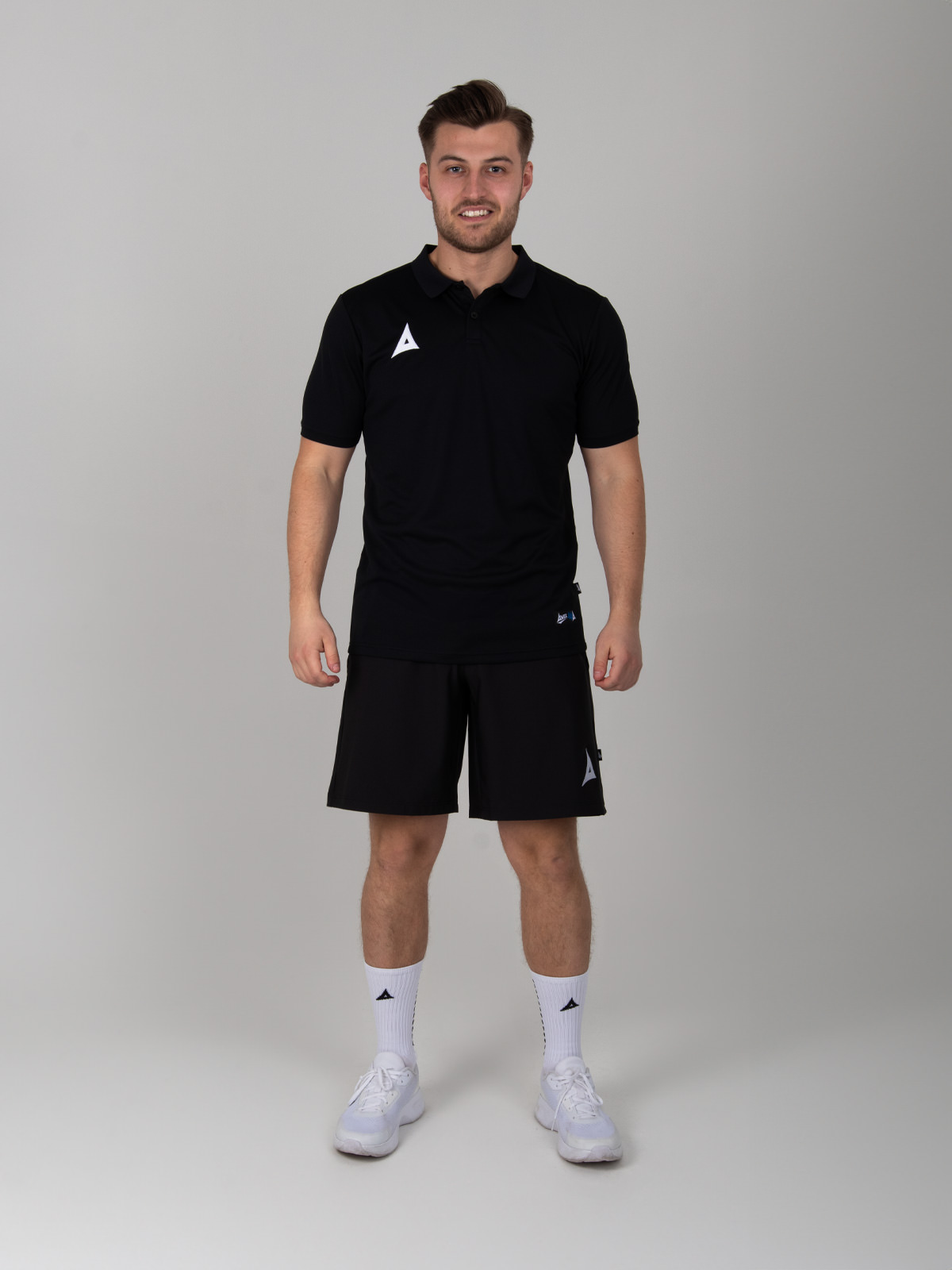 styled man wearing a black polo shirt with black tech short and grip socks