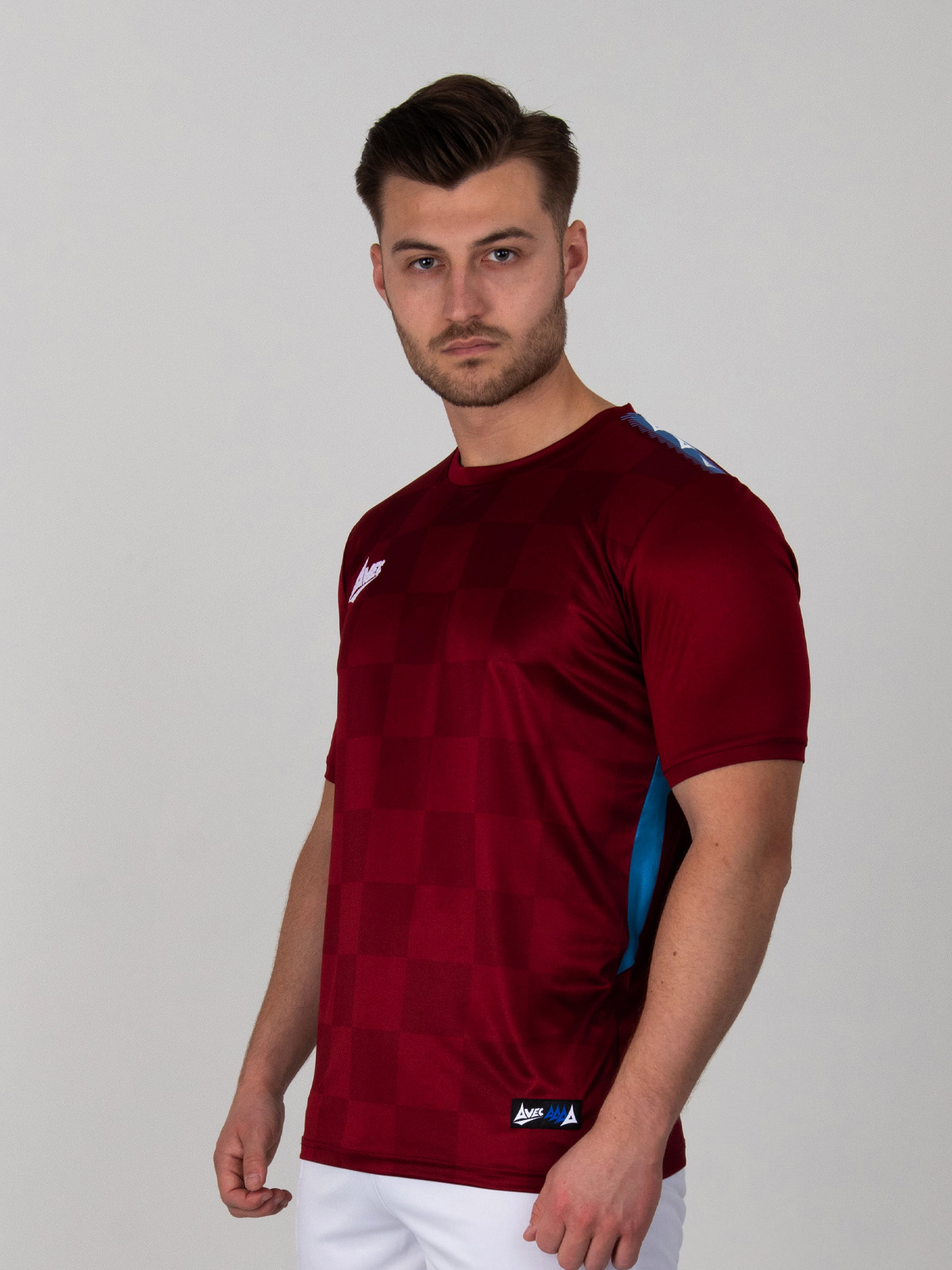 man is wearing a chequered claret football shirt with claret trim