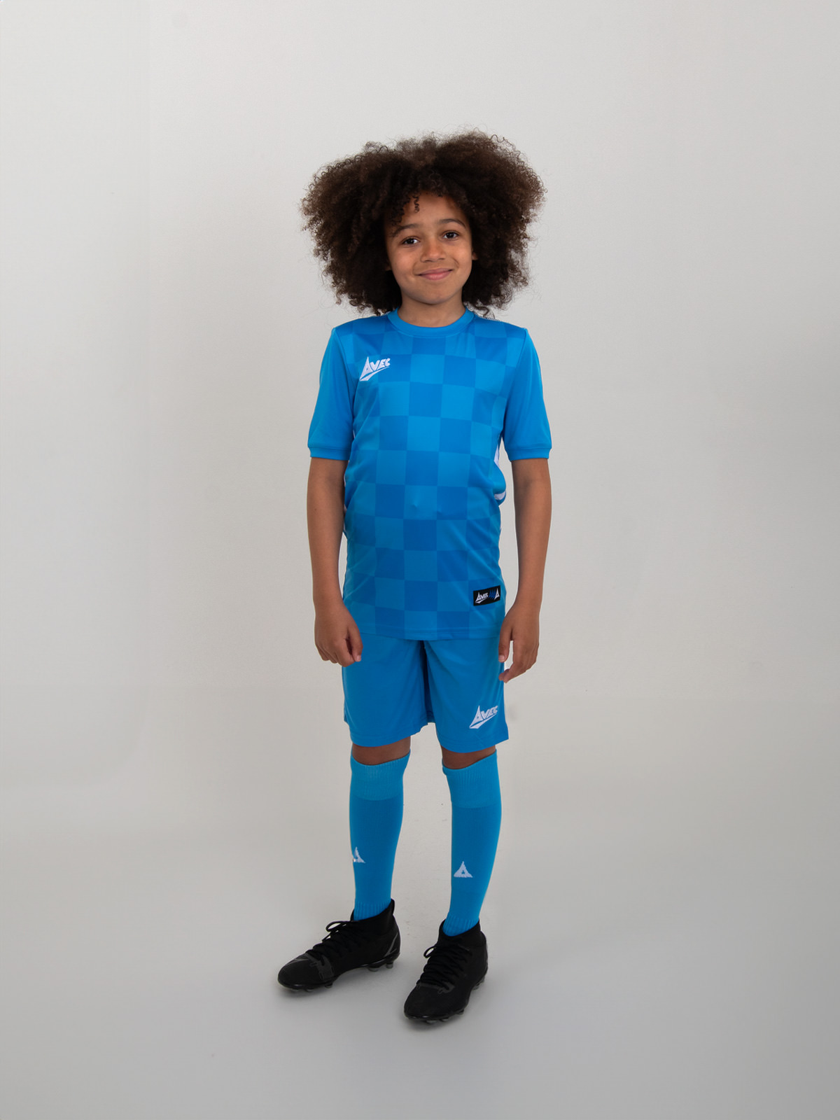 a juniors full sky blue football kit is being worn. the shirt has a tonal chequerboard design
