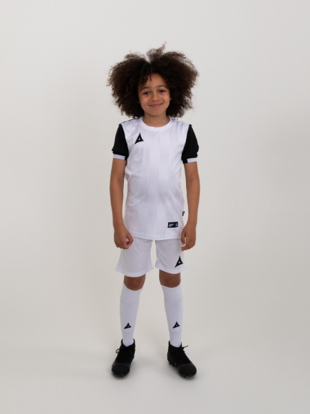 A child is wearing a white football kit with black sleeves and trim. This combination is using white shirt, white shorts and white socks