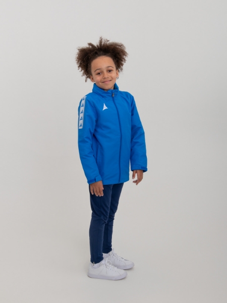 A junior rain jacket is being worn by a child and is paid with navy trackie bottoms