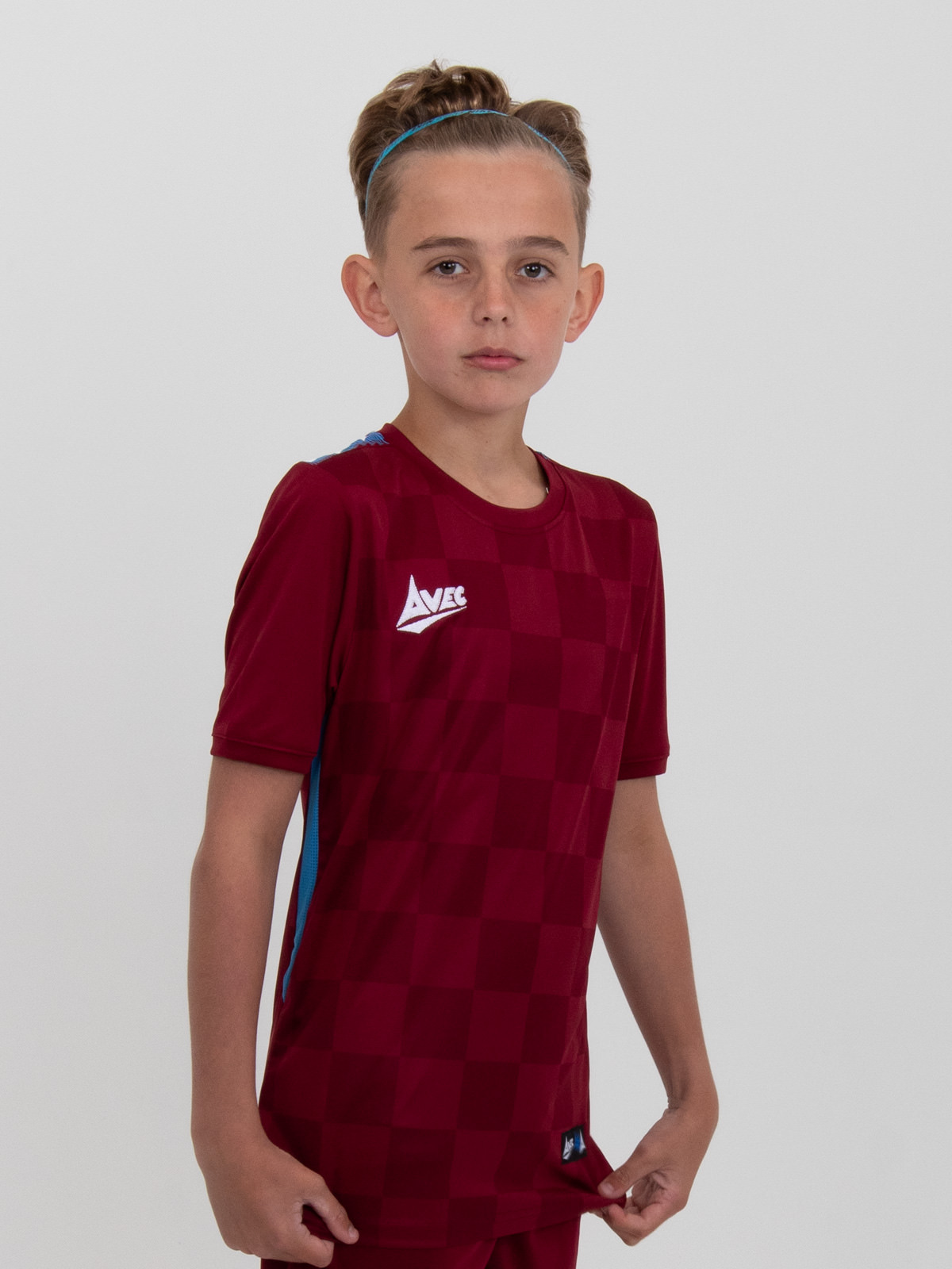 a kid is wearing a claret football shirt with sky blue panels