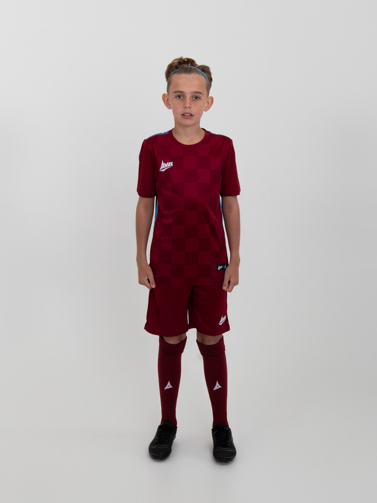 a young boy is wearing a full claret football kit with sky blue trim