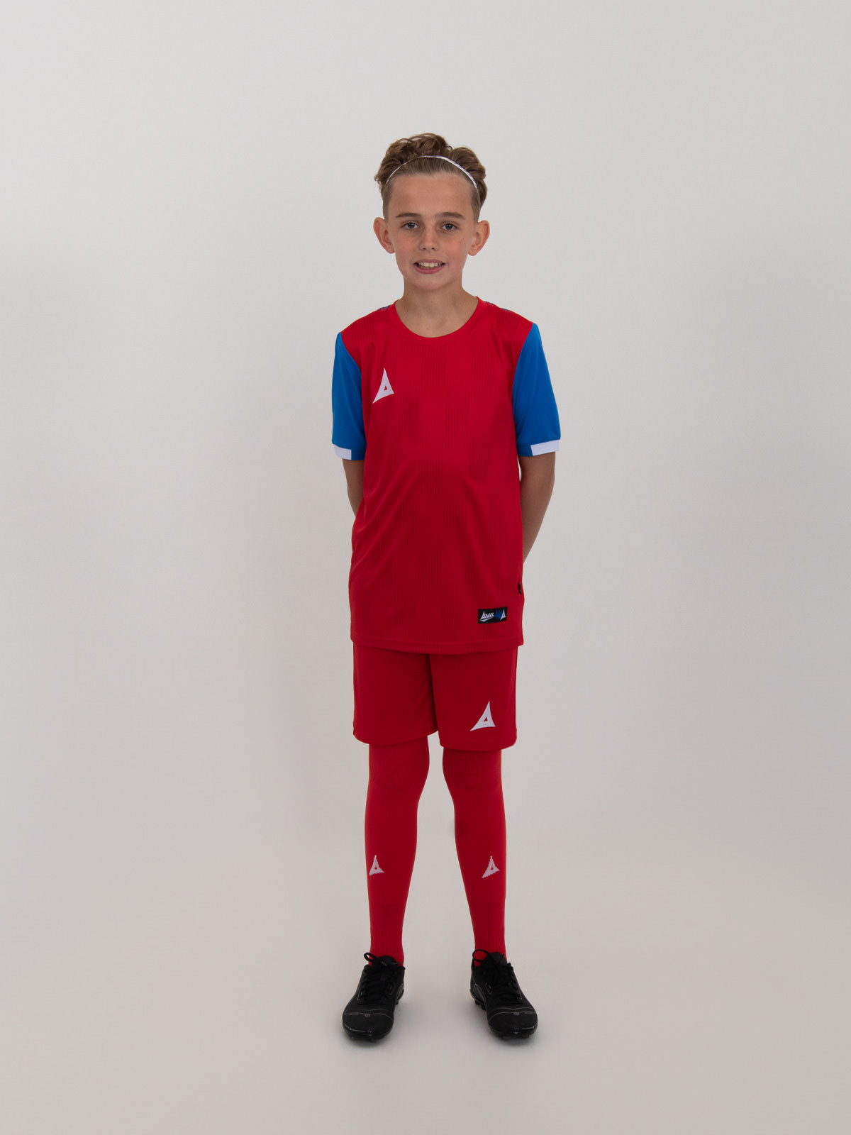 a kids red football kit with royal blue sleeve is being worn.