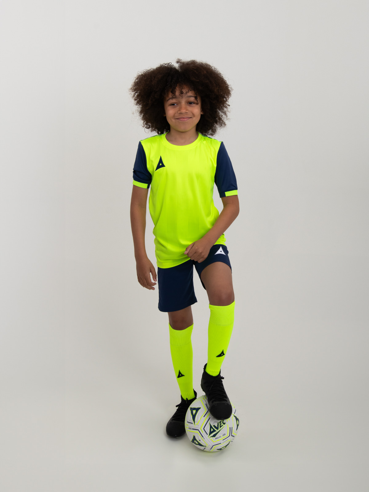 stand out in the new neon yellow football kit from avec sport. the junior is modelling a neon yellow shirt with navy sleeves, and is combined with navy shorts and neon yellow socks.