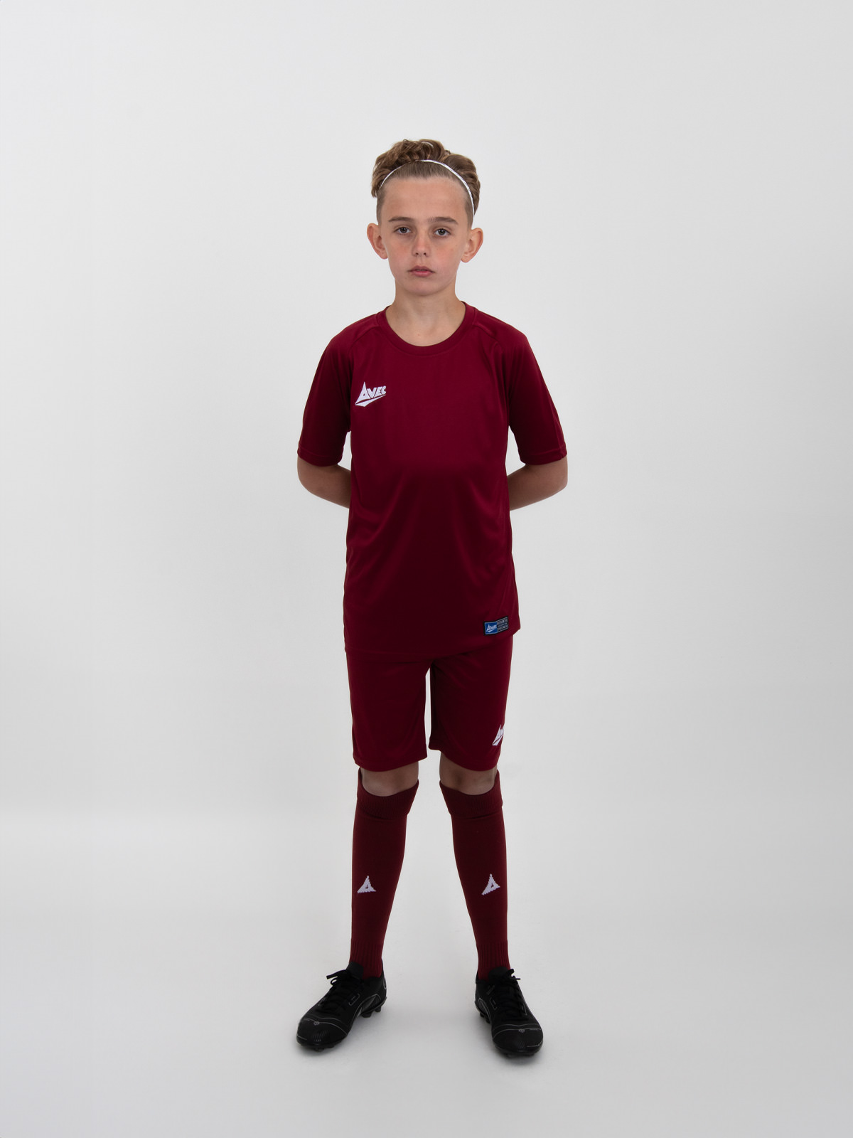 a child is wearing a full plain claret football kit