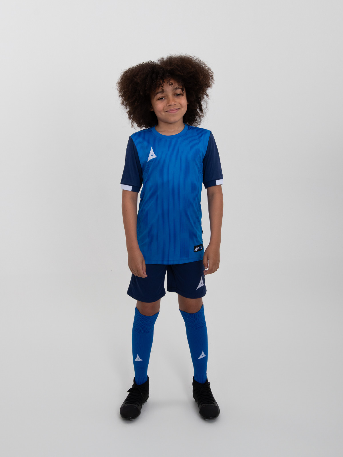 a young child is wearing a royal blue football kit, navy shorts and royal blue socks.