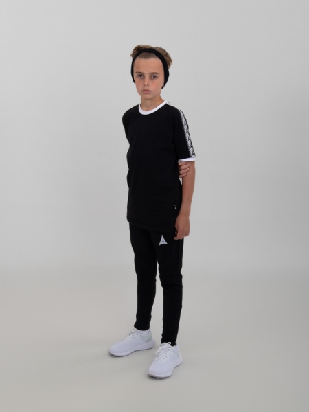 This young child is wearing a cotton t-shirt in black with some black tracksuit bottoms