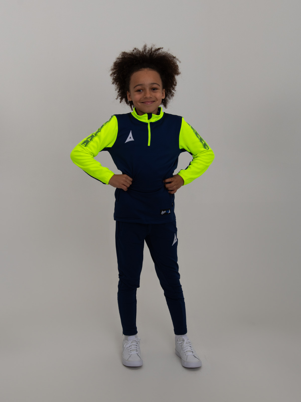 a kid with is hands on his hips wearing a navy blue sweat top with neon yellow sleeves.