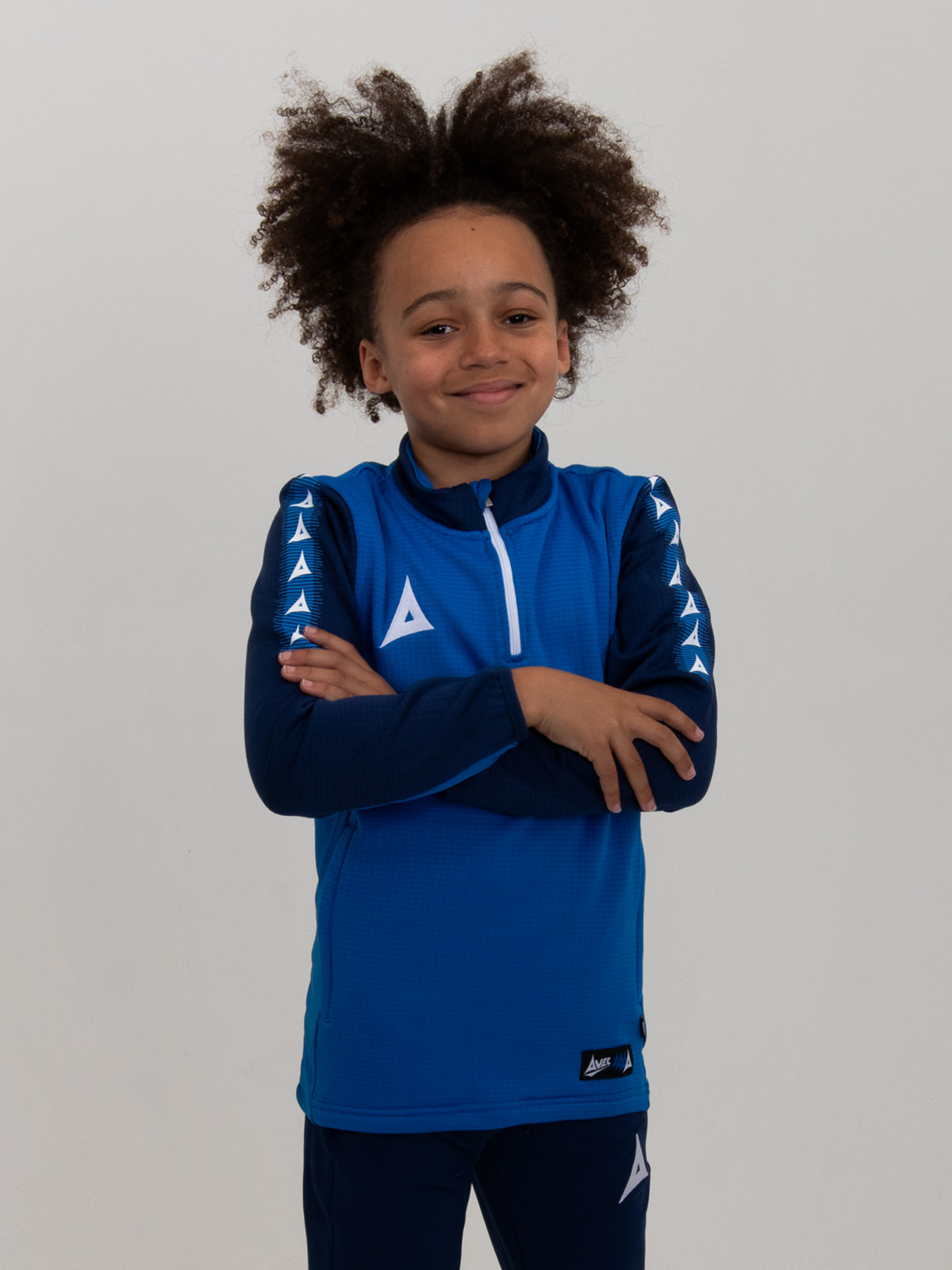 with his arms folded, this young boy is wearing a soft and comfortable royal blue and navy jumper with a zip.