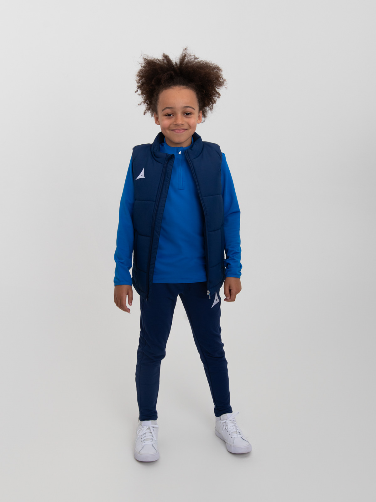 a boy is stood up with an unzipped navy padded gilet
