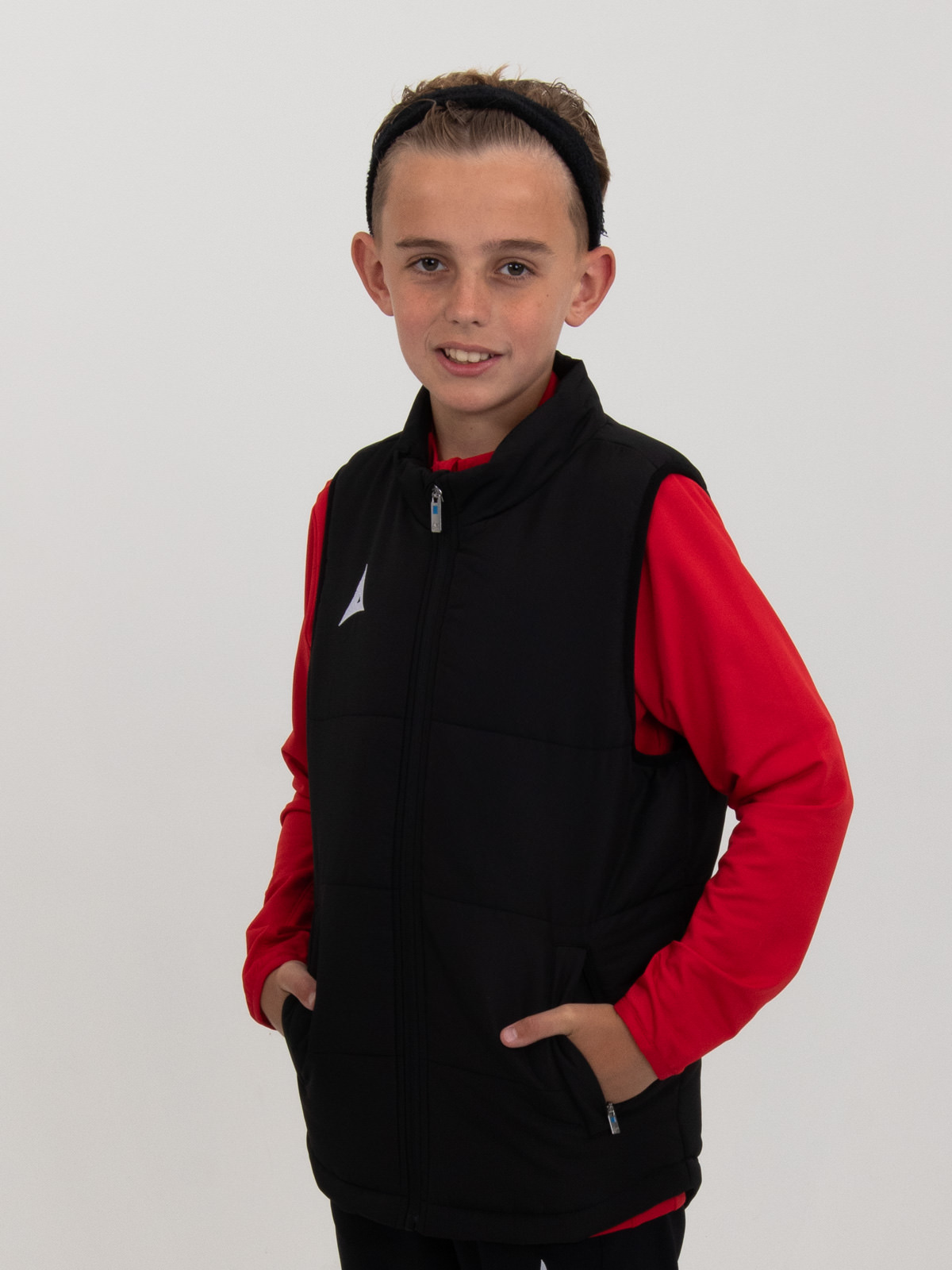 a child is wearing a black padded gilet over the top of a red jumper
