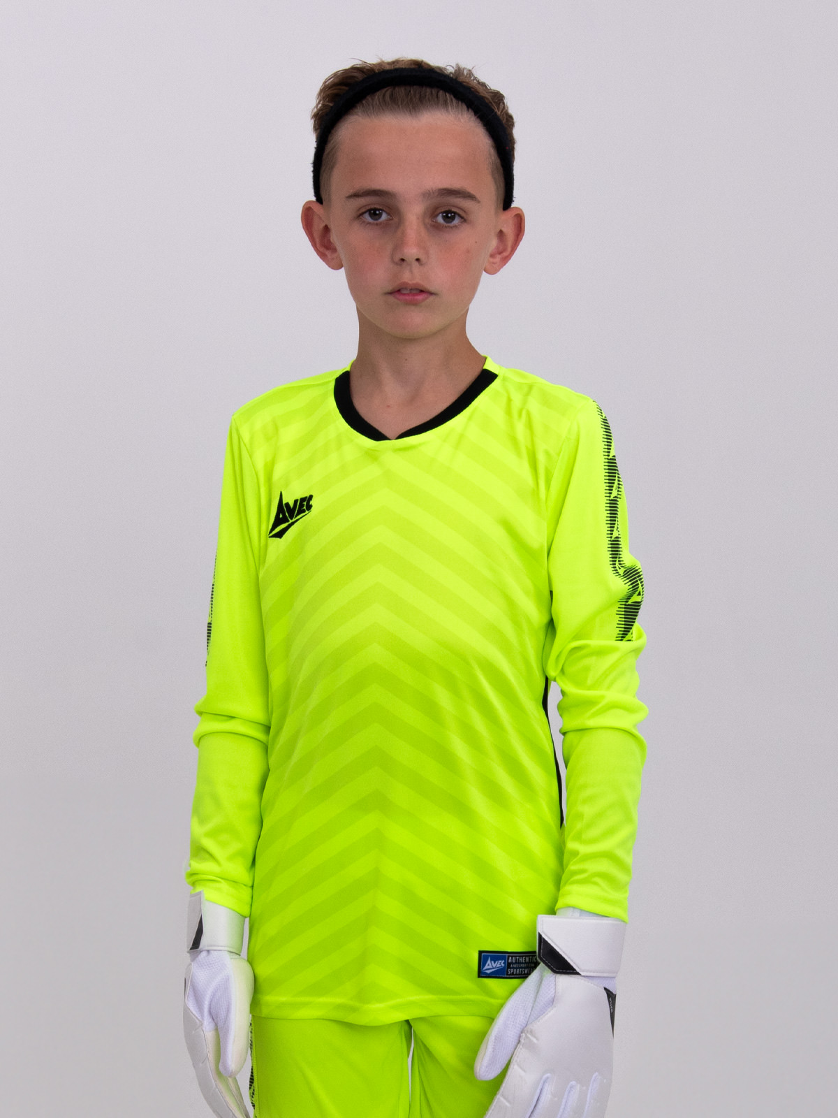 this child is wearing a neon yellow goalkeeper shirt, which has a graphic print on the front.