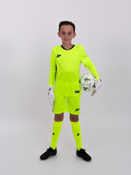 A boy is holding a football, whilst wearing a childrens yellow football kit.