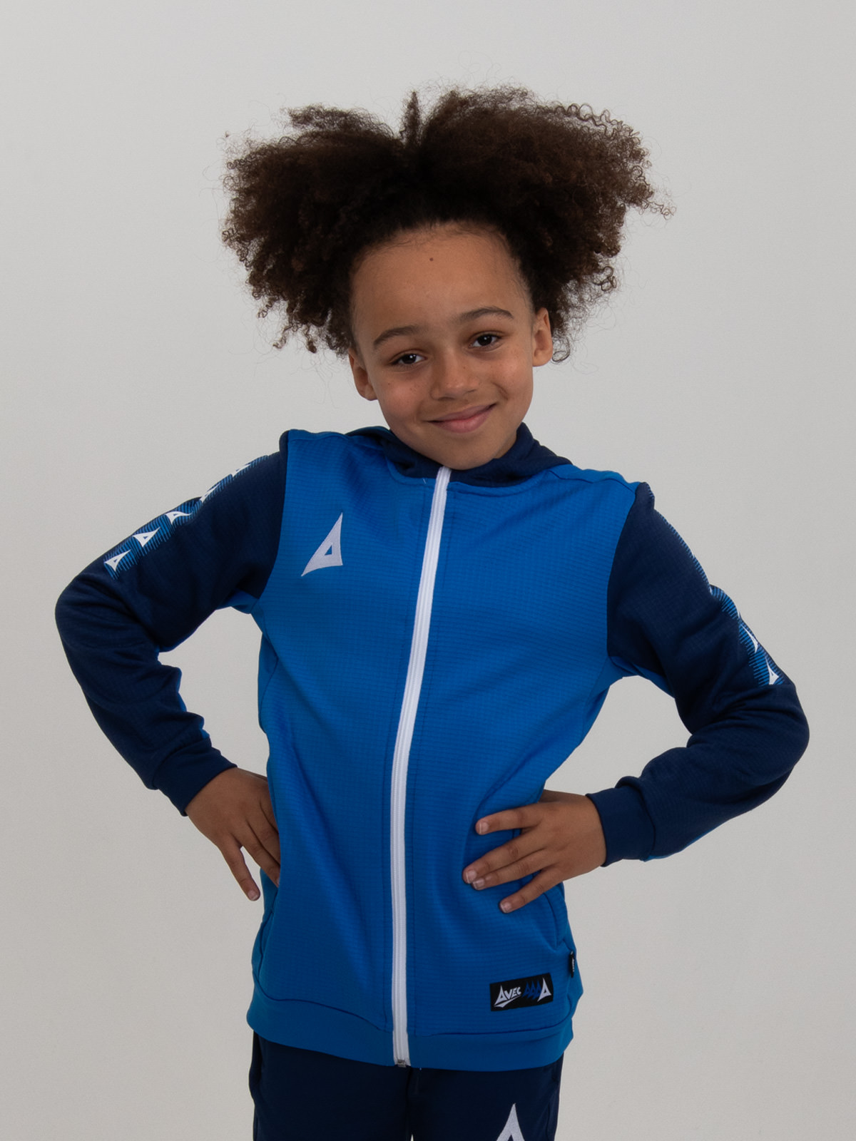 with his hands on his hips, this child is wearing a royal blue hoody.