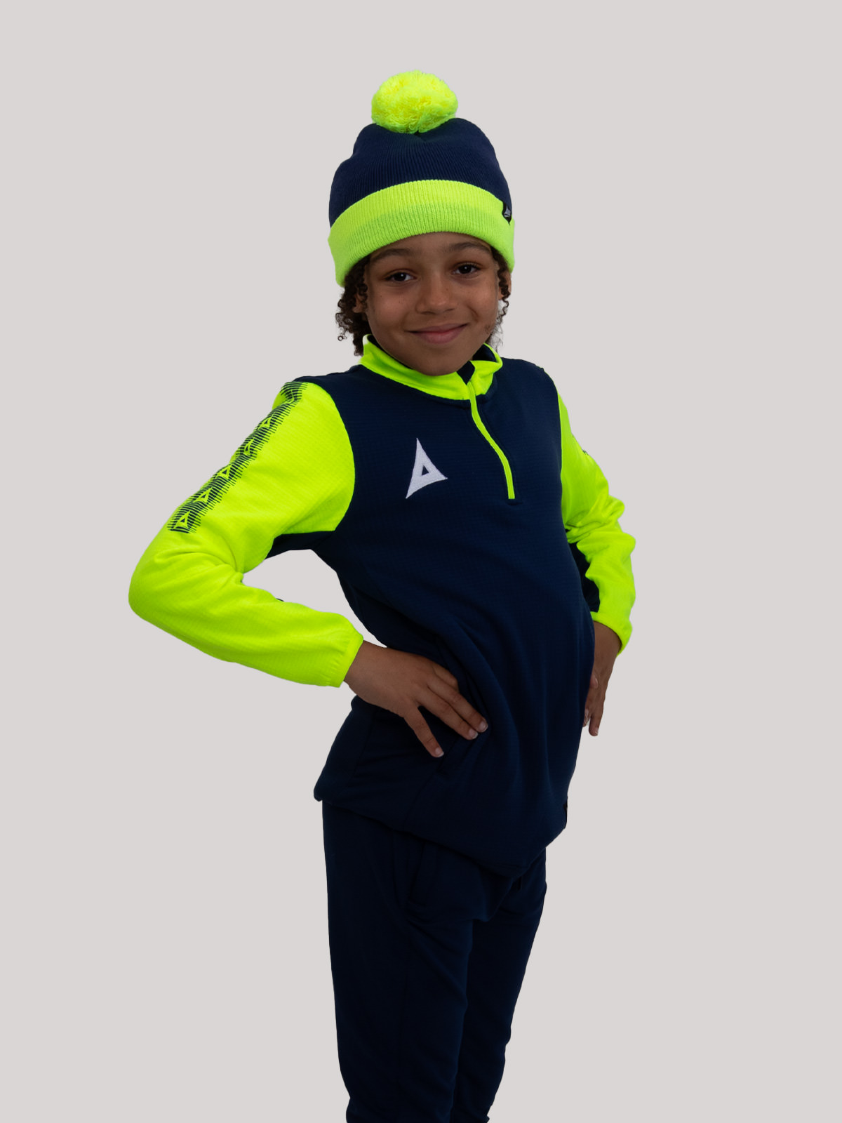 this child is wearing a junior bobble hat in navy and yellow, which can be worn as part of our pro player colleciton.