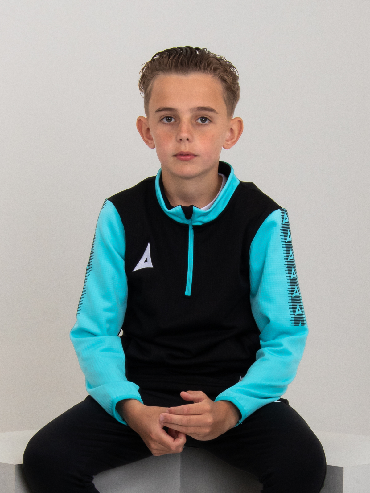 a young child is wearing a black quarter-zip jumper with light blue sleeves