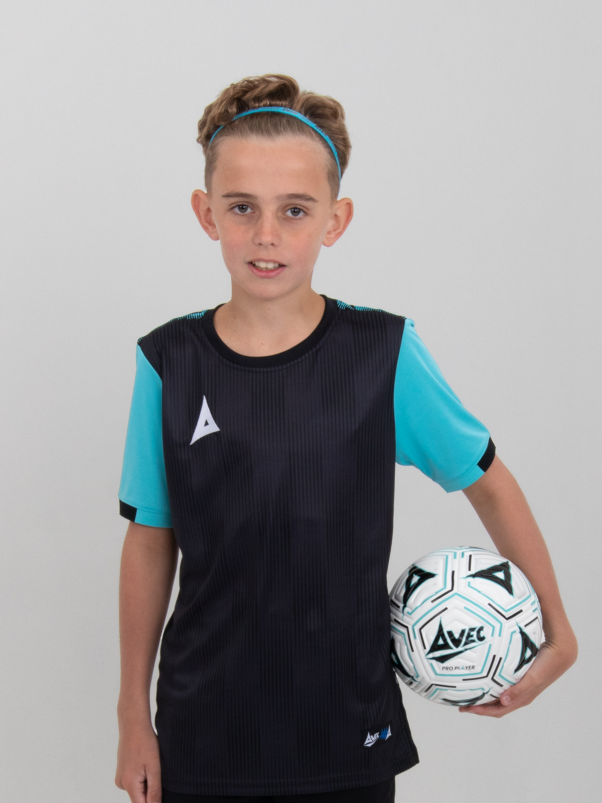 a boy is holding a size 4 football and is wearing a black football shirt with light blue sleeves