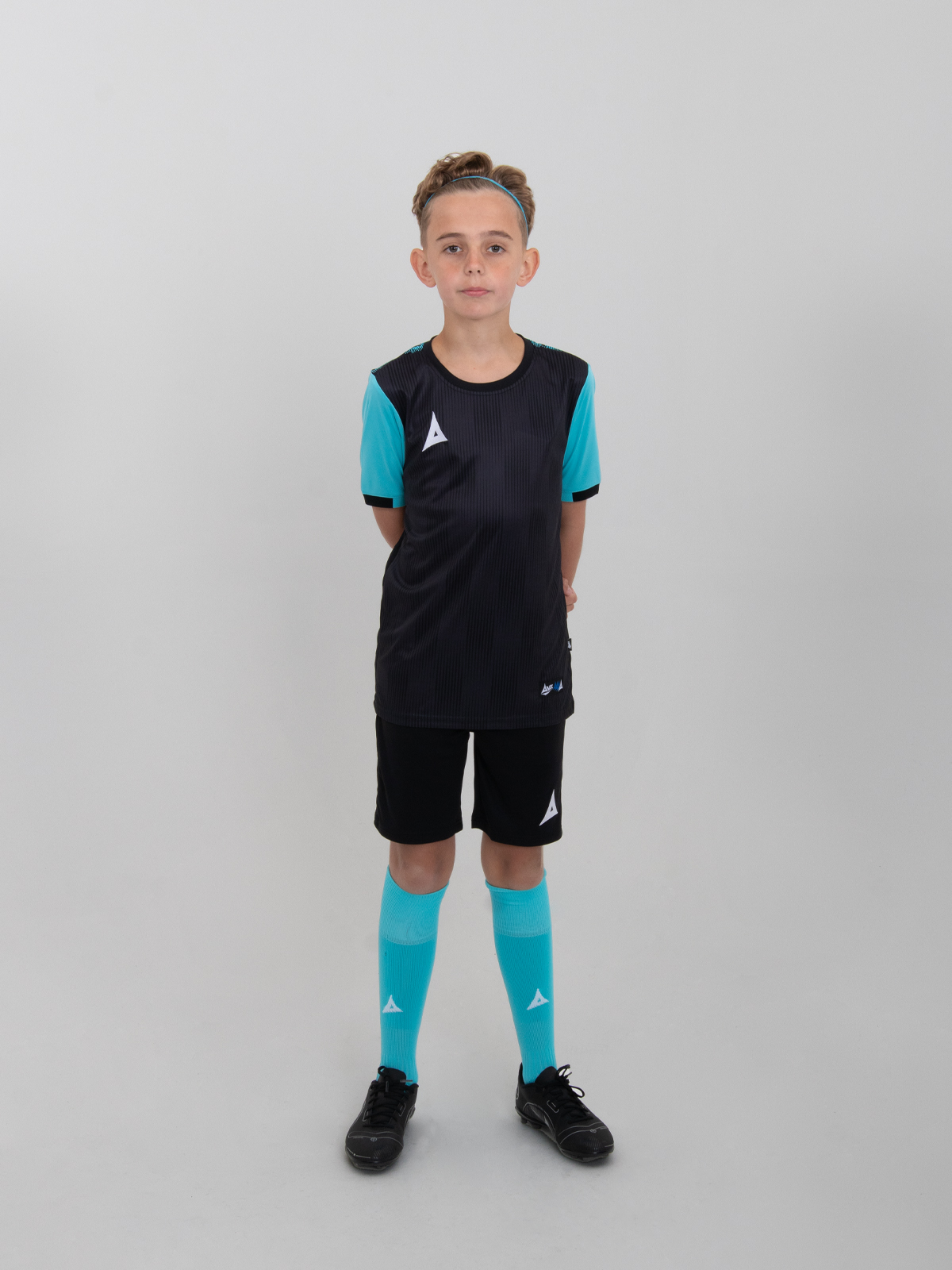 a junior model is wearing a childrens black football t-shirt, black shorts and black football socks