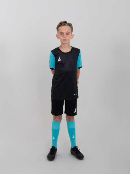 A junior model is wearing a childrens black football t-shirt, black shorts and black football socks