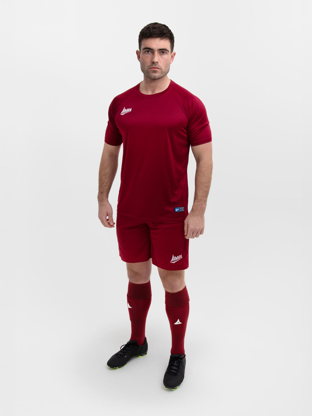 an adult man is wearing a full plain claret football kit