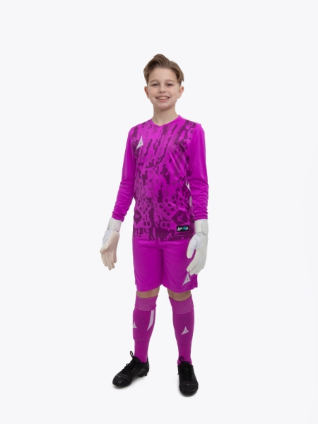 A kid standing up wearing a magenta goalkeeper football shirt, magenta Shorts and magenta Football Socks.