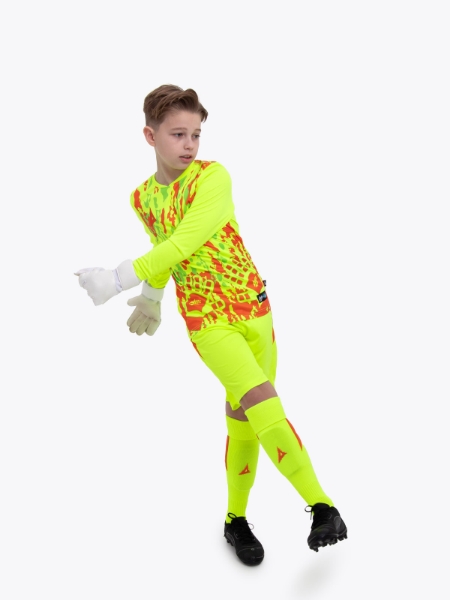 A kid is wearing a neon yellow goalkeeper football shirt with orange panels and detailing