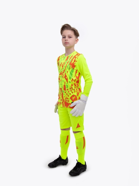 A young boy is wearing a full neon yellow goalkeeper football kit with an orange trim and detailing