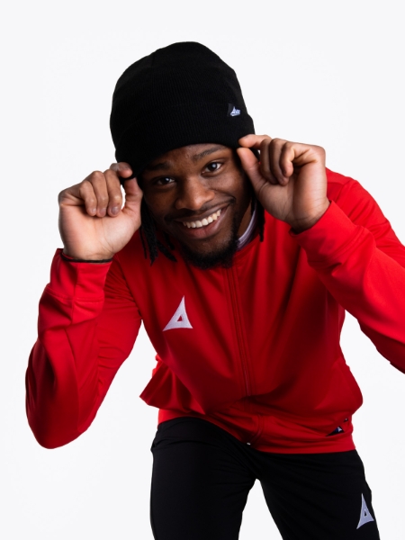 A Man wearing a black beanie hat with a red track jacket on