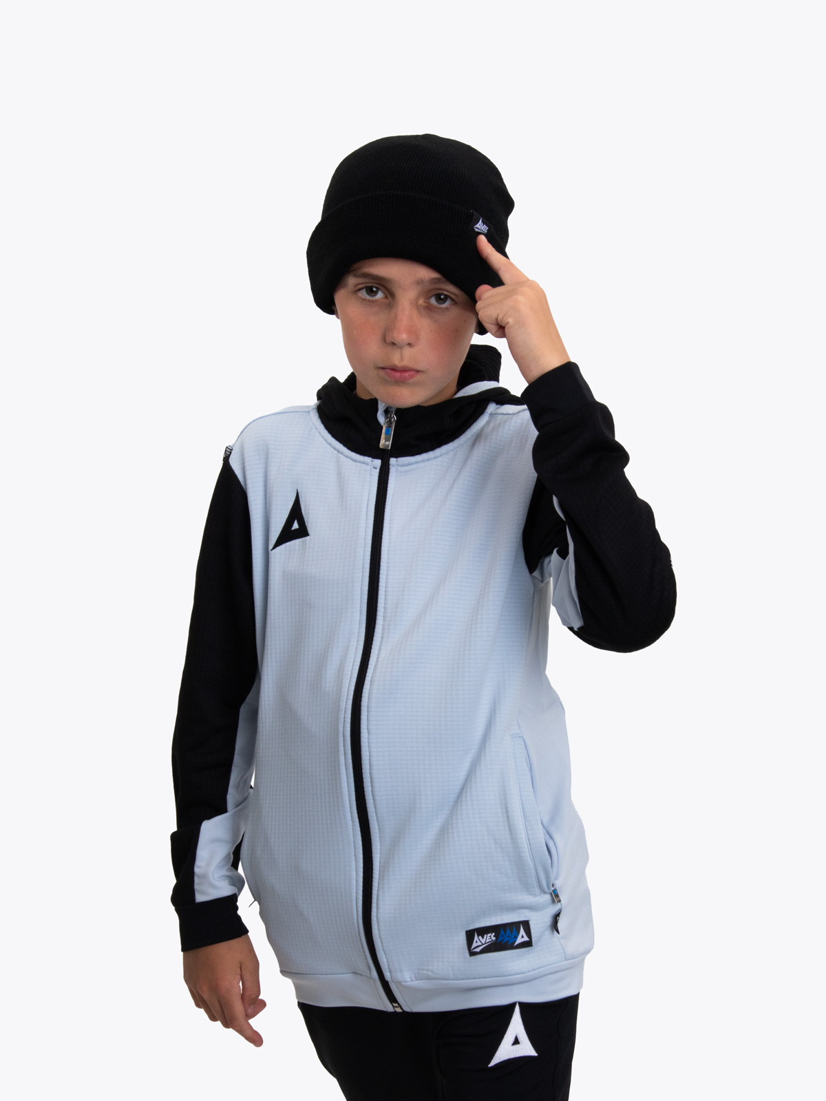 a young boy wearing a black beanie hat with a grey and black track hoodie with black tech pants
