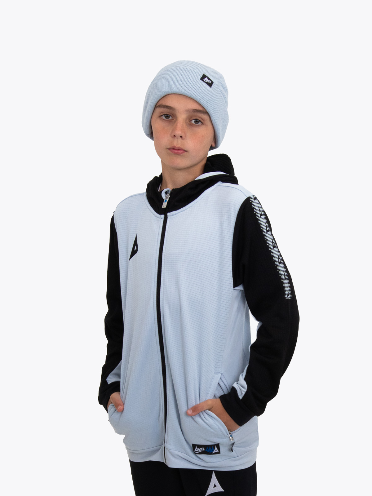 a junior model wearing a matching grey beanie and overlay with black accents and black track pants