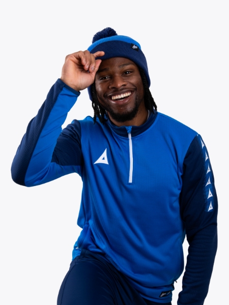 A man wearing a royal and navy blue bobble hat matching his overlay