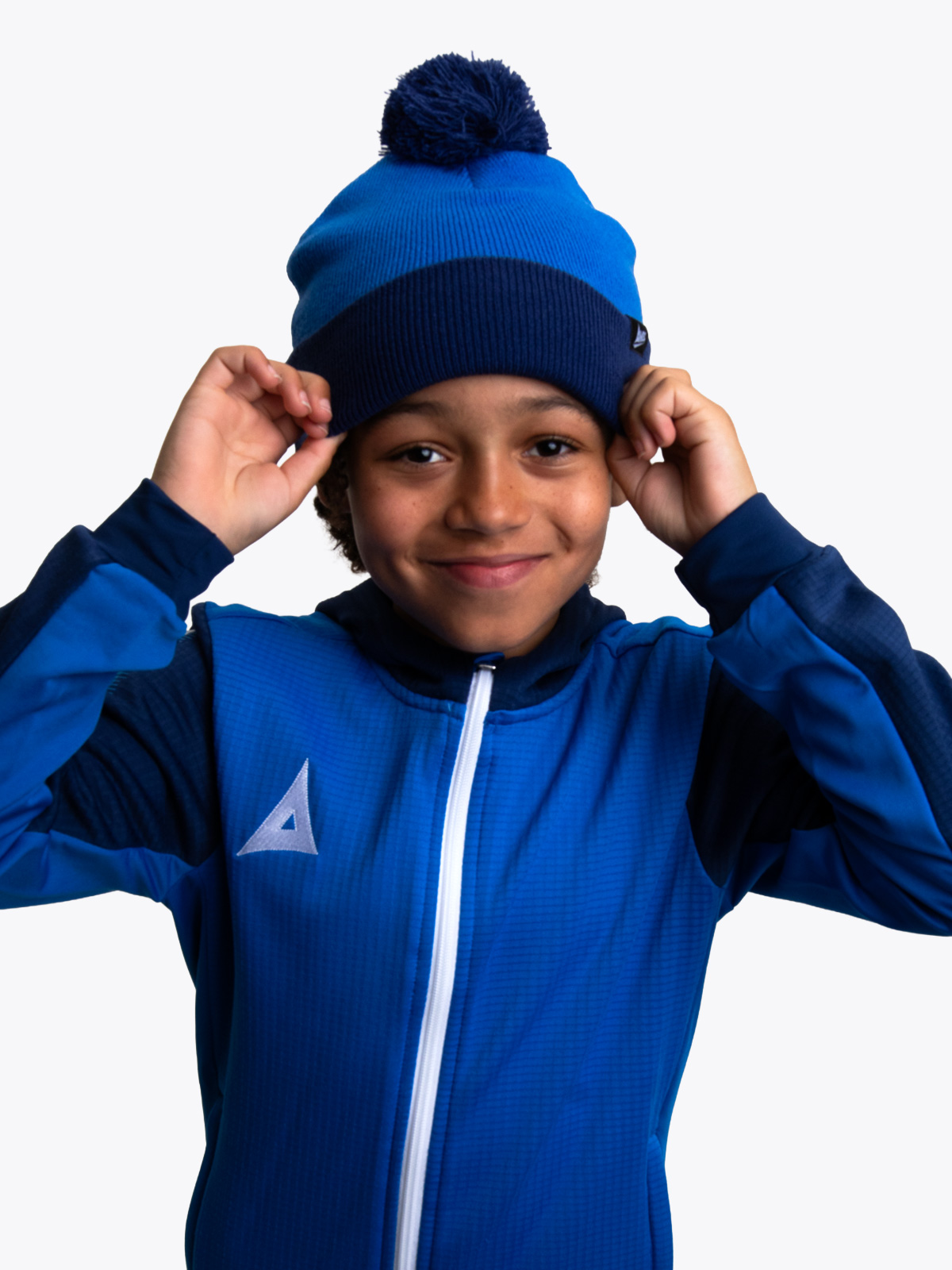 a young boy is wearing a royal and navy blue bobble hat matching his overlay