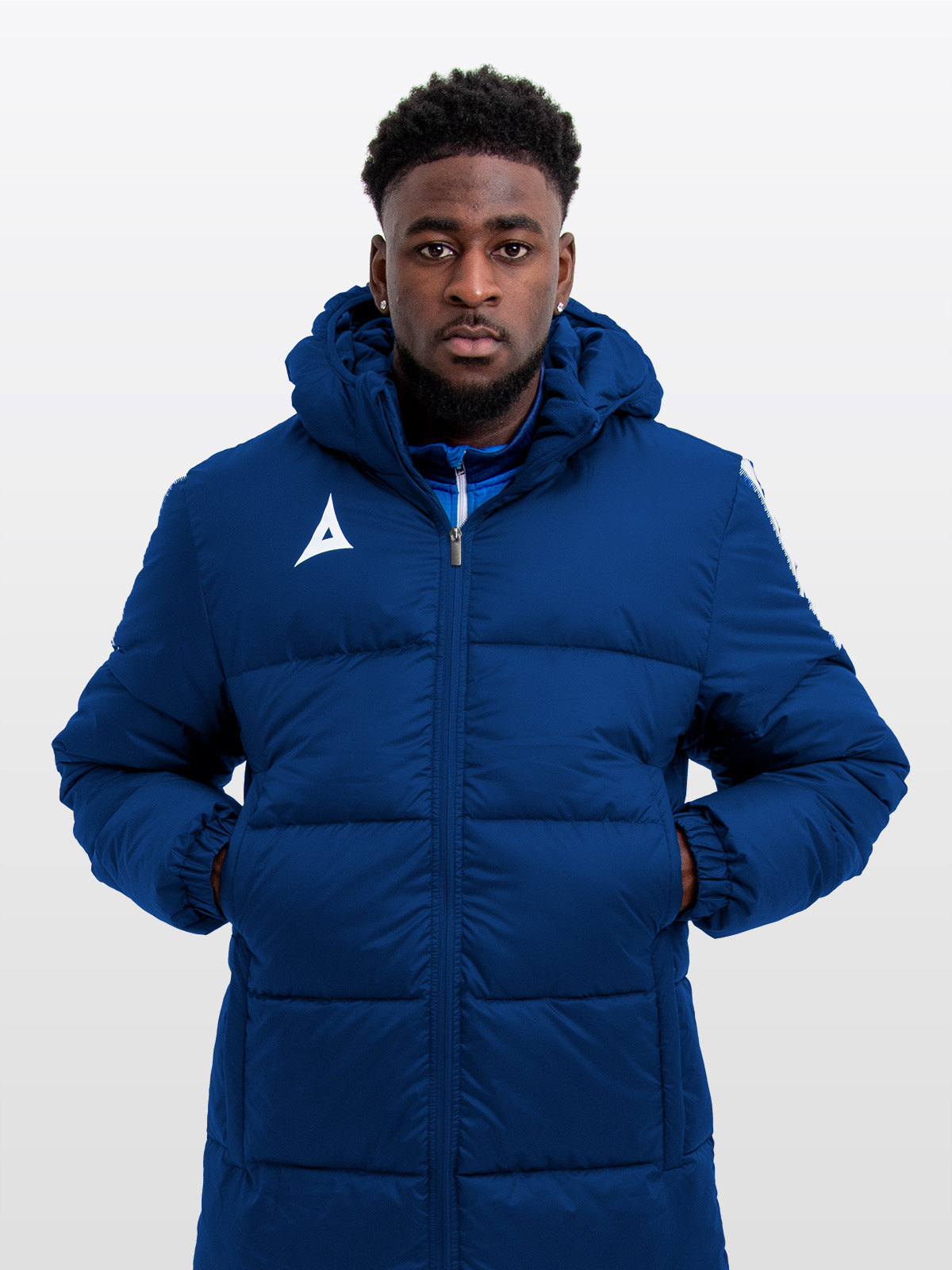 male model wearing the avec evolve pro bench coat in navy, featuring insulated padding and panel detailing for premium warmth and pitch-side comfort.