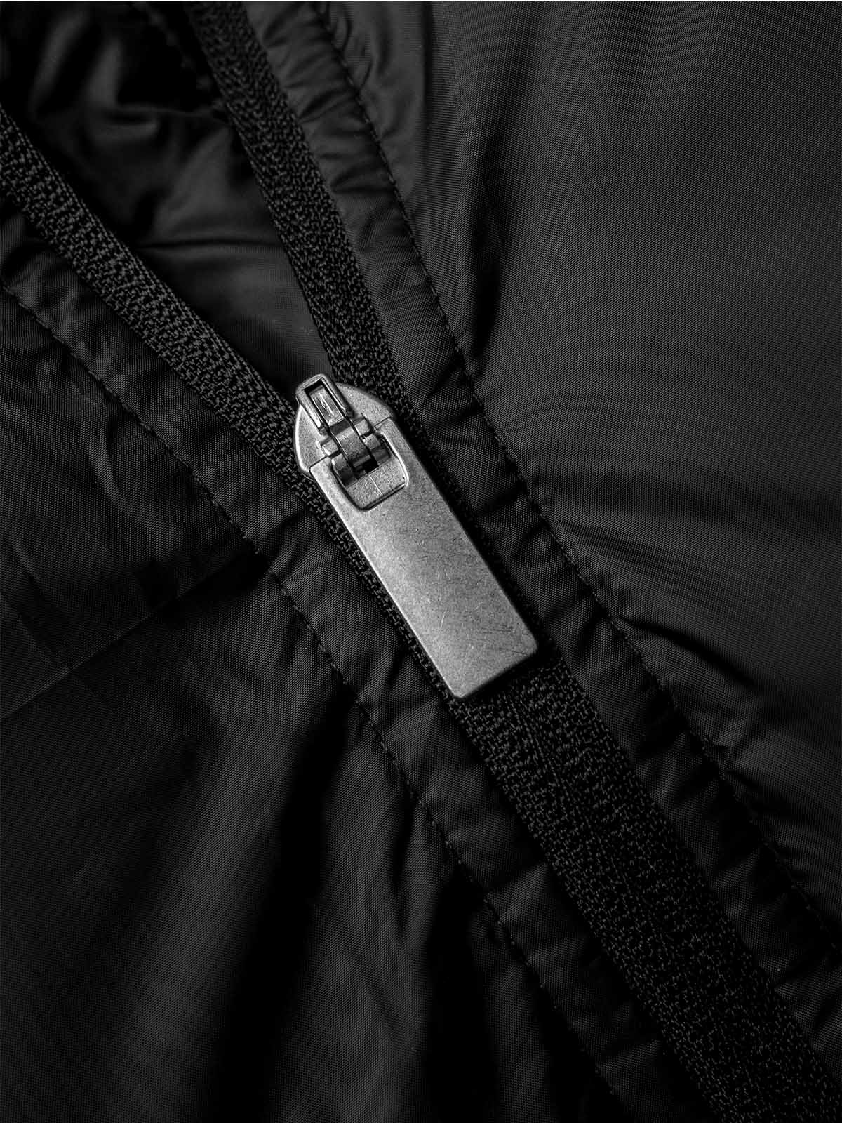 close up of the zipper of the avec evolve pro padded bench jacket in black