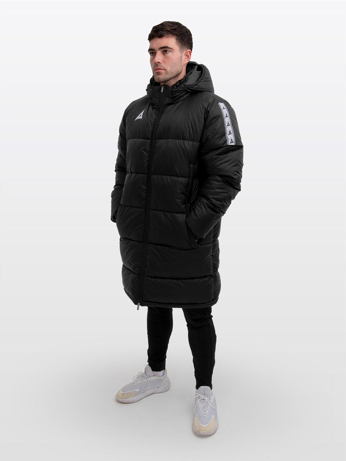 male model wearing the avec evolve pro padded jacket in black with sewn-in panel detailing and medium fill. matching black focus 2 track pants for a styled, professional look