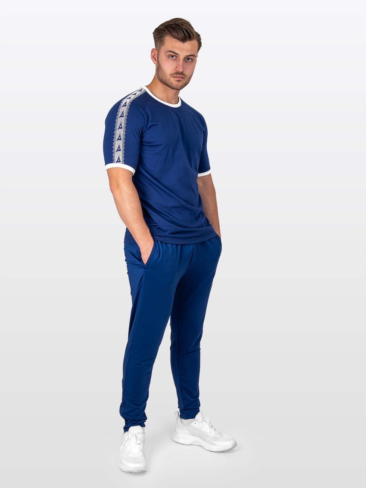 a male model stood wearing the avec evolve navy t-shirt, with ribbed sleeve cuff and neck in white and matching navy avec focus 2 track pants