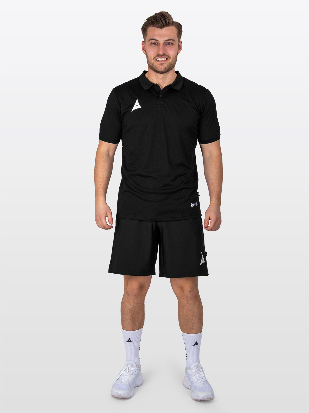 a male model is stood wearing the avec focus 2 black  tech polo, plain black top and the avec focus 2 black tech short
