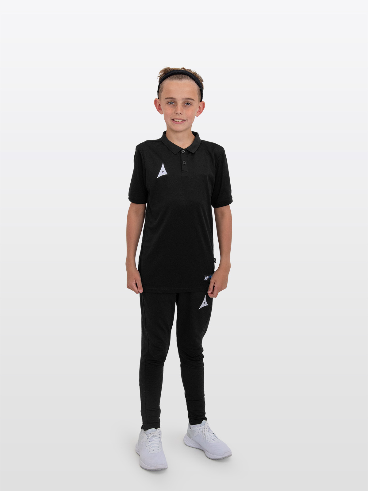 a boy is stood wearing the avec focus 2 black tech polo and the avec focus 2 black tech pant ready for training