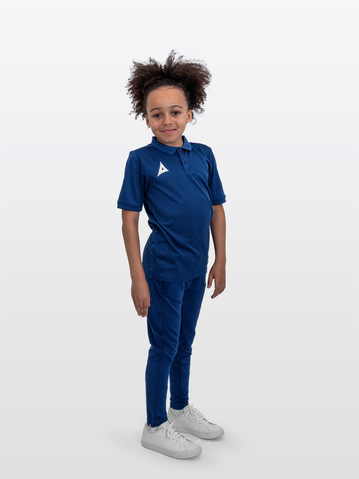 a boy is stood wearing the avec focus 2 navy tech polo and the avec focus 2 navy track pant for a smart combination