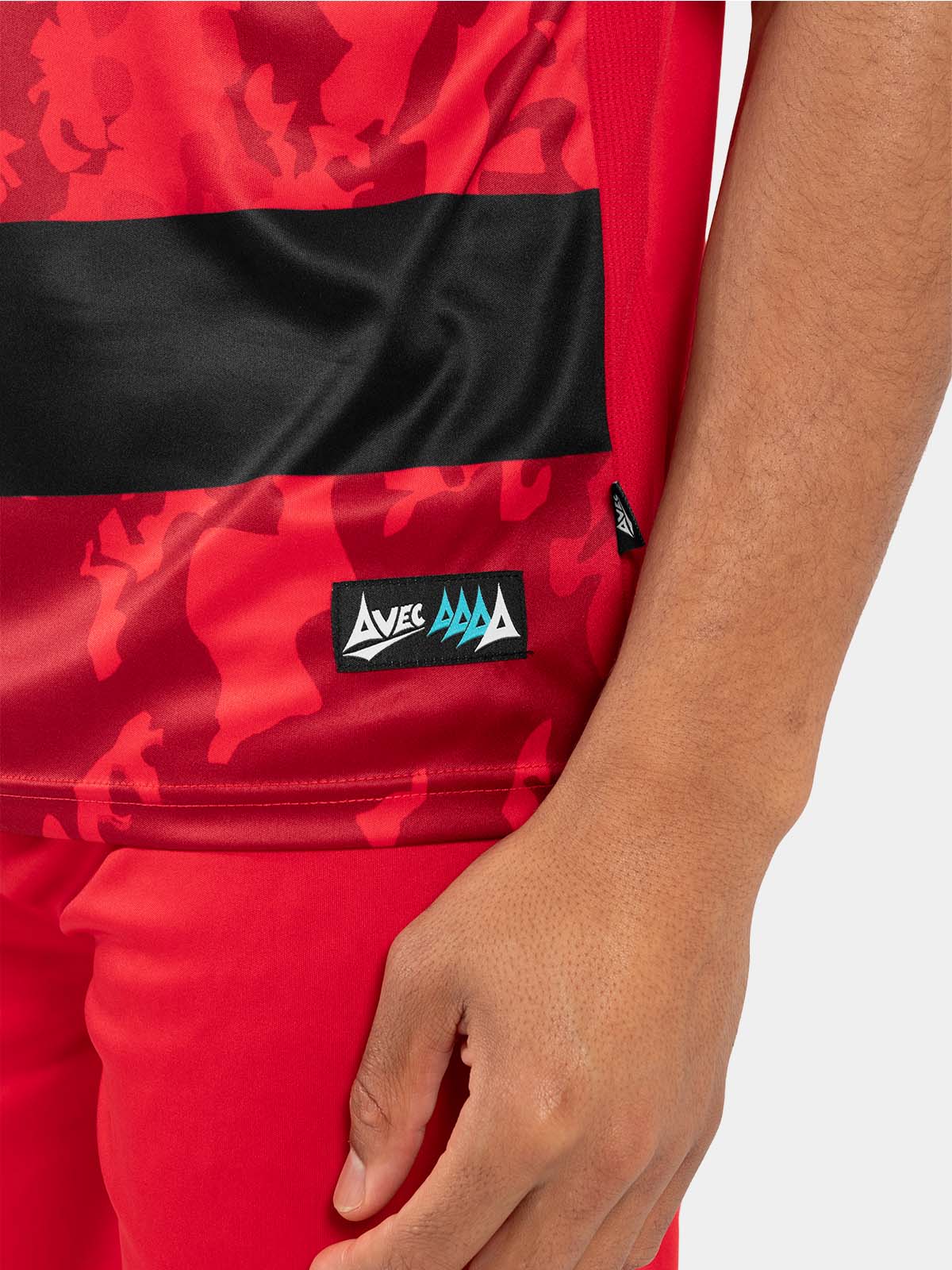 side hem view of the red and black jersey, showing the official authenticity label and moisture-wicking mesh.