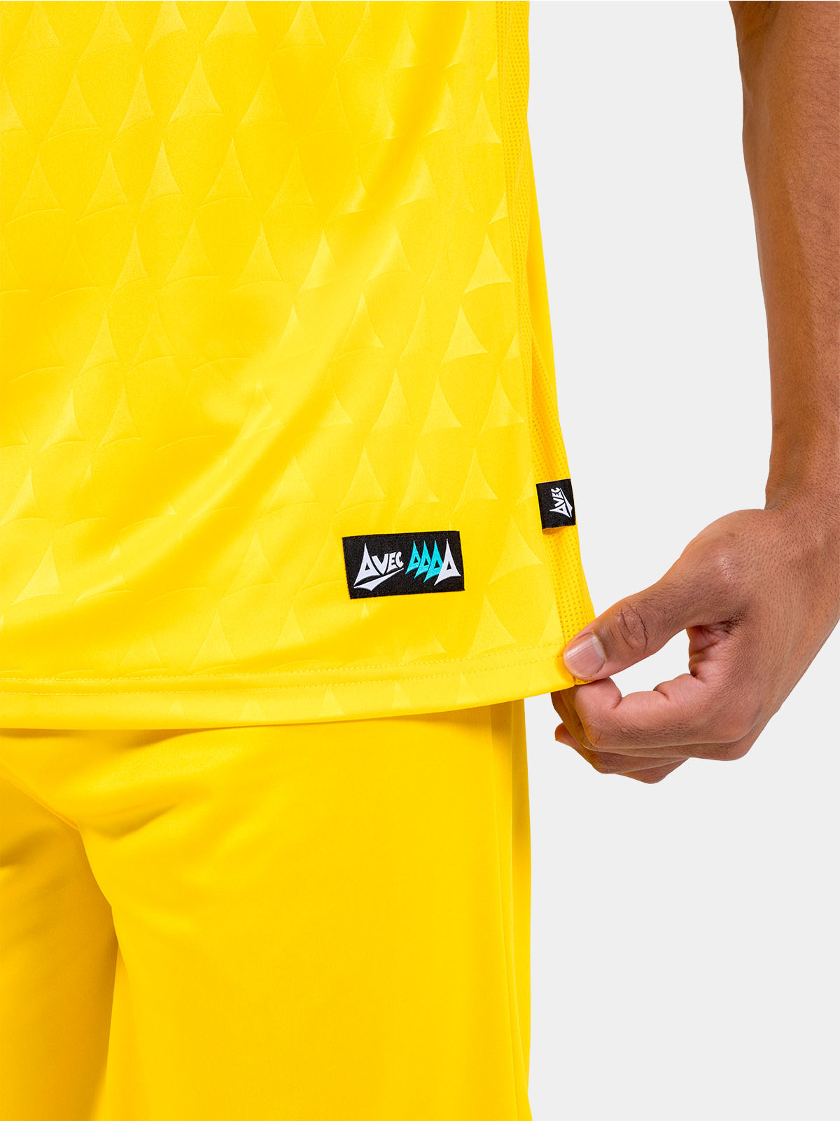 lower hem detail of the yellow heritage jersey showing the authenticity label and side mesh ventilation.