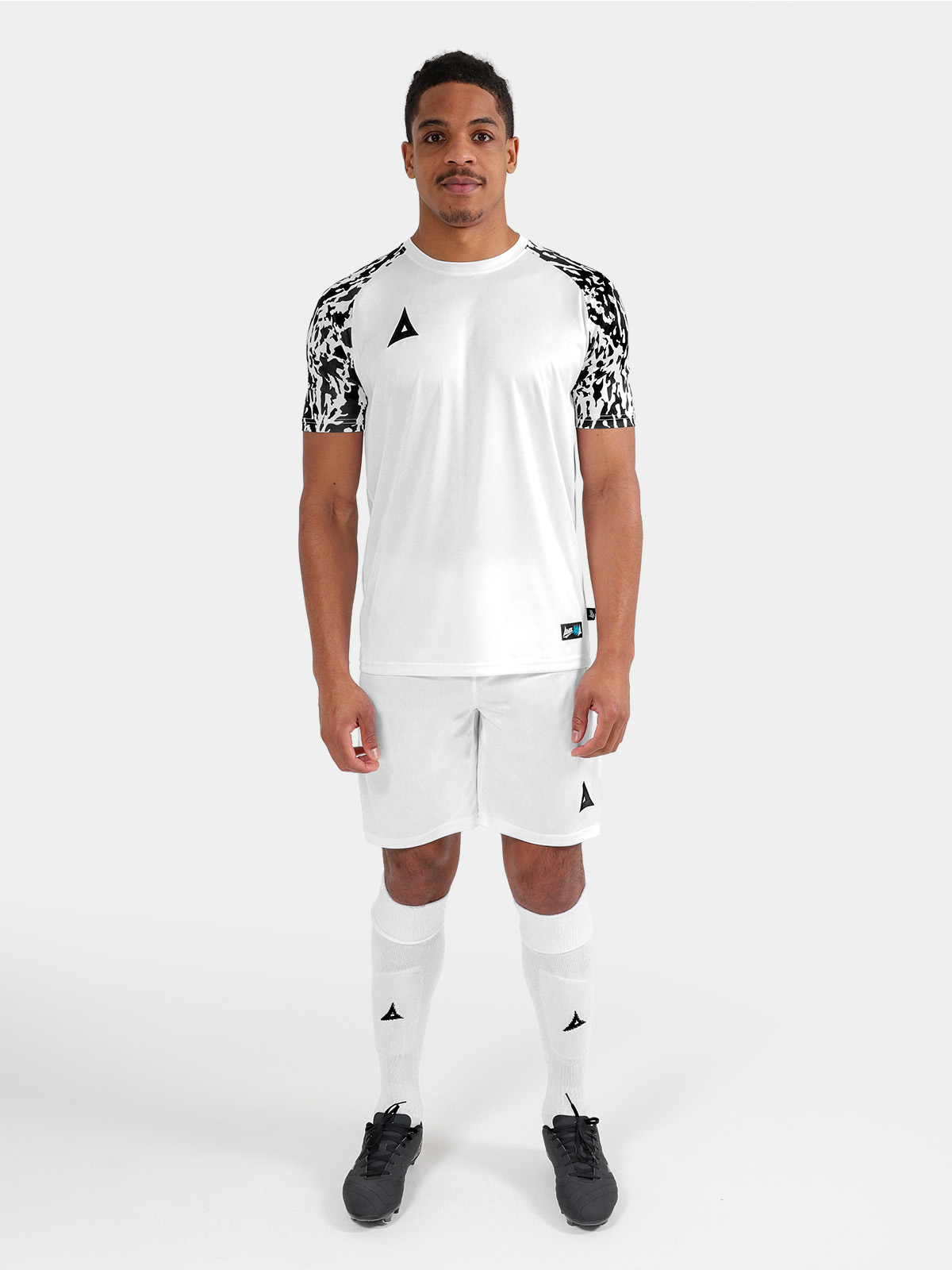 full matchday kit view of the white and black jersey on-model, paired with matching professional teamwear shorts and socks.