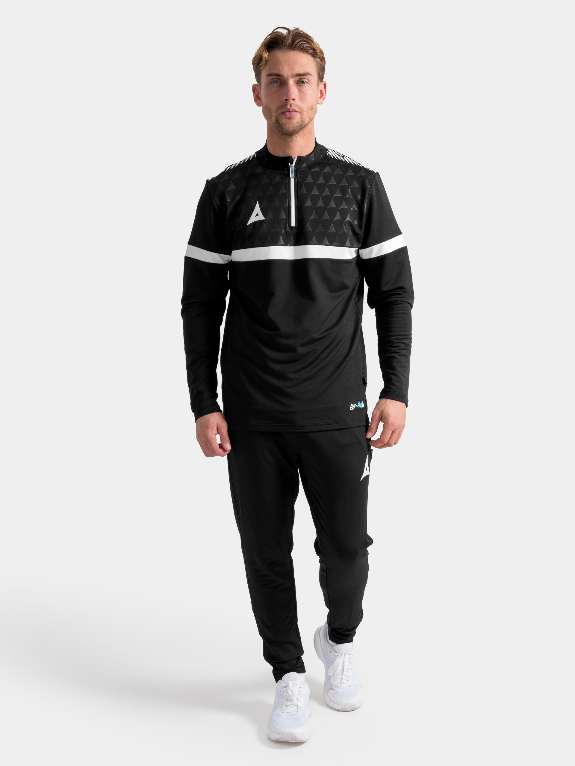 full-length view of the black evolve pro training kit, featuring the 1/4 zip overlay paired with matching technical tapered trousers.